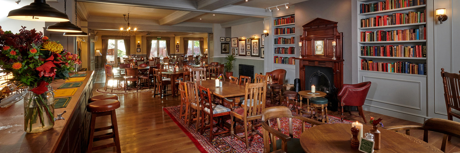 The view from the bar with the internal doors open to the larger function room. Tables and chairs in both rooms with large windows in the background